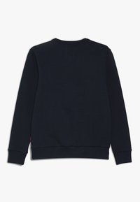 Felpa nera con maniche lunghe, colletto e polsini a costine, e una texture liscia. Presenta un piccolo etichetta sul lato sinistro.