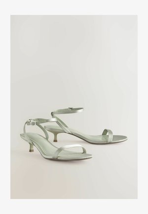 Rihmad, kontsaga sandaalid heledas rohelises satiinis, millel on õhuke pahkluu rihm, avatud varvas ja sihvakas kitten-konts, minimalistlikus disainis.