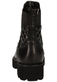 Botte cheville en cuir noir avec un design matelassé texturé, des clous en métal et une semelle plateforme robuste. Elle est dotée d'une languette pour un enfilage facile.