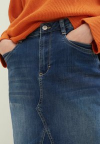 Modré džínové kalhoty s jemným vyblednutím, designem s pěti kapsami a žlutým šitím. Spárovány s oranžovým žebrovaným svetr.