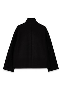 Veste noire oversize avec un col haut, des manches larges et une finition lisse et texturée. Présente une couture centrale dans le dos.