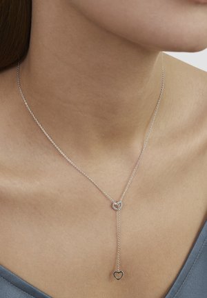 Silberne Halskette mit doppeltem Herzanhänger, zarter Kette und Tropfendesign mit einem kleineren Herz am Ende. Glatte Oberfläche.