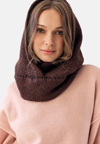 Brązowy, dziany szalik z kapturem o grubym splocie, noszony luźno wokół szyi. Połączony z miękkim różowym swetrem.