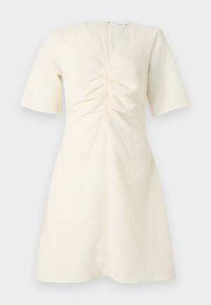 Robe courte à manches courtes en crème avec encolure en V, détail froncé à l'avant et tissu texturé floral subtil, longueur genou avec fermeture éclair au dos.