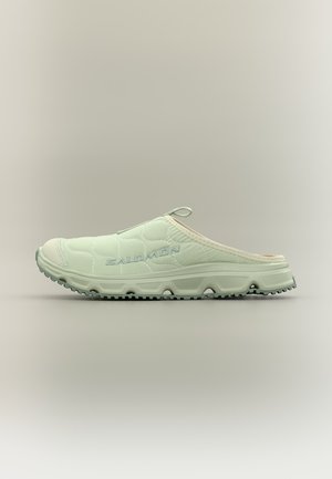 Zapato deportivo exterior de color verde claro con parte superior de tela acolchada, lengüeta en la parte superior y suela de goma texturizada, nombre de la marca visible en el lateral.