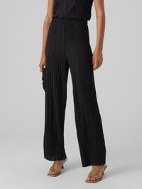Pantalons larges plissés noirs avec une taille élastique, associés à un haut assorti. Le matériau présente une texture douce et un design fluide.