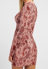 Rotes Kleid mit floralem Muster, langen Ärmeln, einer figurbetonten Form, strukturiertem Stoff und einem einfarbigen Ausschnitt.