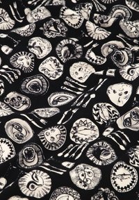 Zwarte stof met gedetailleerde witte illustraties van cirkelvormen, gezichten en speelse patronen, met een gevarieerde, textuurrijke uitstraling.
