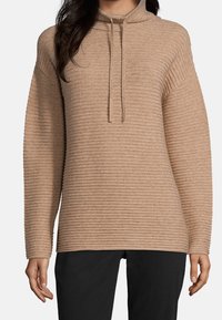 Beige ribbat tröja med hög krage och dragsko; har lång ärm och en avslappnad passform för komfort.