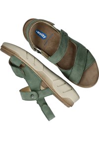 Groene leren sandalen met gekruiste banden, verstelbare enkelband en een beige rubberen zool met textuur voor grip. Merkenlogo zichtbaar aan de binnenkant.