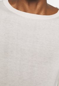 Lichtbeige gebreide trui met een brede, ribgebreide halslijn; zachte textuur; glad, gelijkmatig weefsel; onversierd ontwerp.