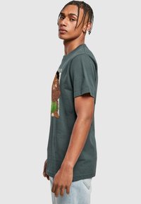 Gray cotton T-shirt featuring a colorful graphic design of a character with leaf accents. Short sleeves and a casual fit.