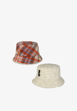 Two bucket hats, one orange and purple plaid wool, the other cream-colored fluffy with a small black label.