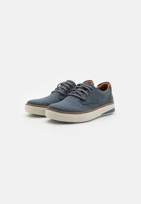 Sneakers in tessuto blu con lacci grigi, dettagli in pelle marrone e suola in gomma bianca con un motivo testurizzato. Design a punta arrotondata.