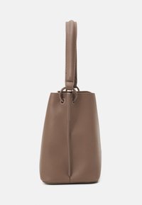 Brun läderbucketväska med en strukturerad form, lång axelrem och cirkulära detaljer. Slät textur med en minimalistisk design.
