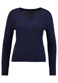 Maglione pullover blu navy con scollo a V, maniche lunghe e orlo a coste. Realizzato in tessuto morbido con una texture liscia e con marchio minimale.