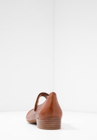 Brązowy skórzany but z zaokrąglonym noskiem i niskim, warstwowym obcasem. Posiada boczne wycięcie i gładką fakturę z minimalną ilością szwów.