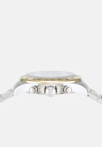 Orologio da polso cronografo in metallo argentato con lunetta d'oro, tre pulsanti, e cassa rotonda. Presenta un quadrante chiaro e un bracciale texturizzato.