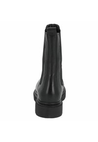 Zwarte leren enkelboot met elastische zijkanten en een gestructureerde afwerking. Heeft een vlakke rubberen zool en een ronde neus.