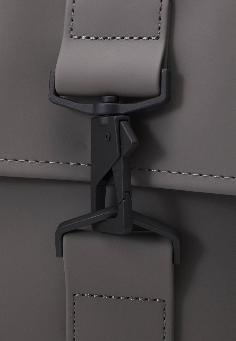 Borsa grigia con superficie texturizzata, dotata di chiusura a fibbia in plastica nera e dettagli di cucitura a contrasto lungo i bordi.