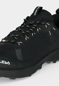 Μαύρο παπούτσι πεζοπορίας με σχοινιά με σχέδια, υφασμένο πέλμα και επιγραφόμενη ταινία έλξης στη γλώσσα, σχεδιασμένο για υπαίθρια χρήση.