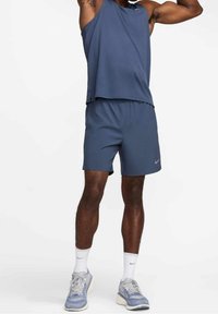 Herrarnas sportoutfit i mörkblått. Består av en ärmlös topp och matchande shorts. Materialet verkar lätt och smidigt. Nike-logotypen synlig.