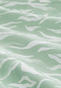 Light green fabric with white wavy pattern. Smooth texture, lightweight, suitable for apparel or home decor. Subtle design details.