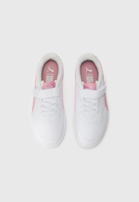 Baskets blanches avec des accents roses, des lacets et des bandes Velcro, vues d'en haut sur une surface blanche unie.