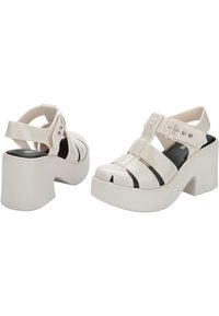 Infradito in pelle verniciata bianca con tacco spesso a piattaforma, design open-toe, cinturini incrociati e dettagli neri nelle sezioni superiori.