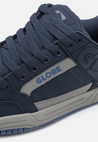 Mornarice s teksturiranom tkaninom, sivoj akcentima i gumenom potplatom. Ima debele vezice i "GLOBE" logotip sa strane. Nizak dizajn.