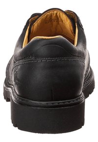 Scarpa in pelle nera con tacco arrotondato, imbottitura gialla, dettagli di cucitura visibili e suola nera texturizzata.