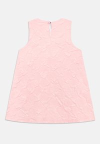 Ermeløs rosa kjole med teksturert bølgemønster, med en knappelukking bak. Glatt stoff med en kne-lengde design.