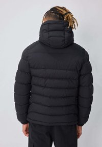 Veste matelassée noire avec un col montant et une capuche ajustable. Présente un design matelassé avec des sections horizontales cousues. Texture douce.
