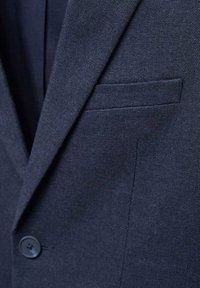 Námořnický blazer z texturované látky, s jednobuttonovým zapínáním a jemnou náprsní kapsou. Výrazné švy a přizpůsobený střih.