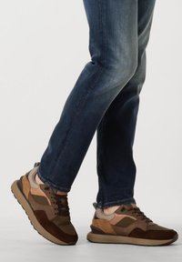 Bruine en beige sportieve schoenen van suede en mesh, met een cushioned zool, vetersluiting en contrasterende kleurpanelen.