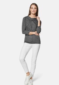 Grijze, gestructureerde langemouwen top met een col en driekwart mouwen, gecombineerd met witte jeans en witte sneakers.