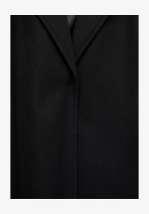 Zwarte wollen jas met een notch-lapel, strakke lijnen en een zachte textuur. Ontworpen met minimale stiksels en een getailleerde pasvorm.