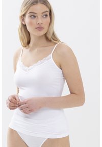 Top in cotone bianco senza maniche con bordo in pizzo lungo il scollo a V, con spalline sottili e una vestibilità aderente. Tessuto morbido e superficie liscia.