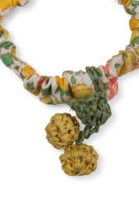 Scrunchie floreale in tessuto giallo, verde e rosa, con un accento intrecciato verde e due palline gialle intrecciate attaccate.