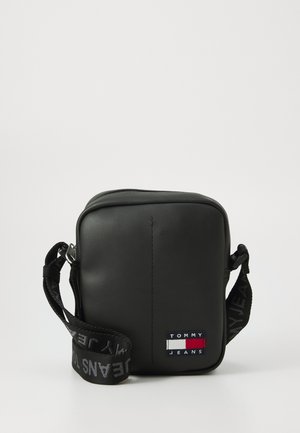 Black synthetic crossbody bag with a square shape, adjustable logo strap, and small embroidered "TOMMY JEANS" patch on the front.
