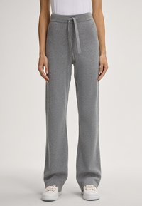 Grijze sweatpants met een brede pijp, een trekkoord in de taille en geribbelde manchetten. Gemaakt van zachte stof, met minimale branding op de tailleband.