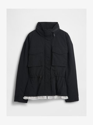 Czarna kurtka z wysokim kołnierzem, zapięcie na zamek, dwie kieszenie z przodu, ściągacz w talii oraz biały koronkowy wykończenie u dołu. Ustrukturyzowany materiał.