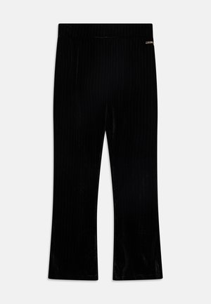 Pantalones acampanados de terciopelo negro acanalado con cintura elástica. Presentan un pequeño detalle metálico en el costado. Textura suave en toda la prenda.