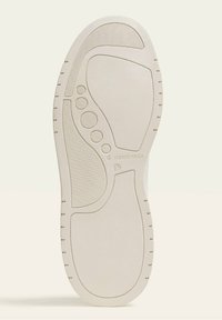 Suola di scarpa in gomma bianca con motivi testurizzati, tra cui righe e forme circolari. Le indicazioni includono "STRADIVARIUS" e taglia 37.