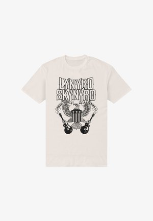 Beige T-shirt med sort tryk af en ørn, der holder to guitarer, og teksten "Lynyrd Skynyrd Sweet Home Alabama" over og omkring ørnen.