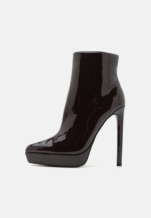 Bottines en cuir verni noir avec un bout pointu, semelle plateforme et talon aigu haut. Finition lisse et brillante avec des lignes épurées.