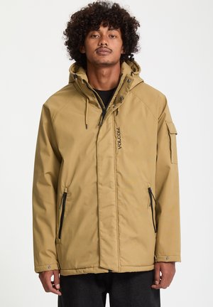Tan waterdichte jas met een capuchon, rits aan de voorkant, zijzakken en verstelbare koordjes. Kenmerkt zich door een logo op de borst en een zak op de mouw.