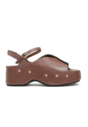 Brązowy skórzany sandał na platformie z odkrytym palcem, złotymi nitami wzdłuż podeszwy i regulowanym paskiem wokół kostki z małą klamrą.