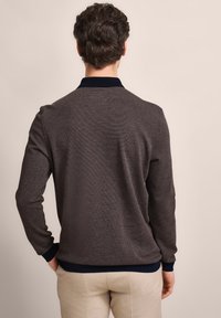 Grau gestrickter Pullover mit langen Ärmeln und einem marineblauen Kragen. Gerippter Saum und Bündchen, strukturierte Stoffdetails, schlichte Rückansicht. Leichtes Design.