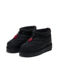 Botas de tobillo acolchadas negras con punta redondeada, suela texturizada negra y herrajes en acento rojo. Material suave y collar acolchado que mejoran la comodidad.